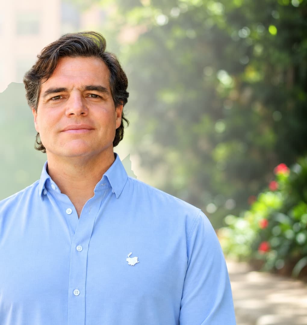 Alejandro Arbeláez A., de camisa azul claro, al aire libre entre vegetación
