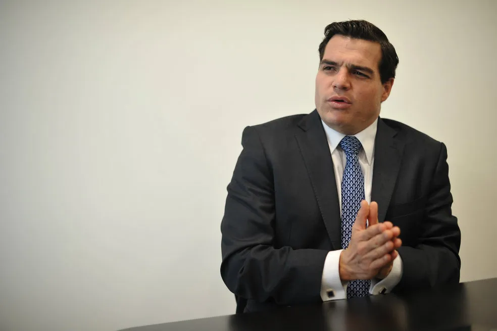 Alejandro Arbeláez habla durante una entrevista, sentado ante una mesa y vestido con traje oscuro