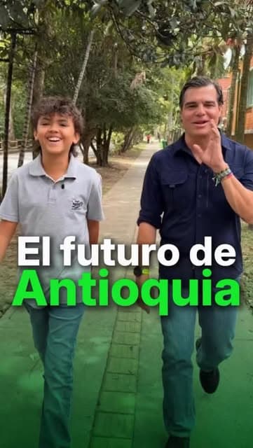 Alejandro Arbeláez camina y conversa con un joven por un sendero arbolado