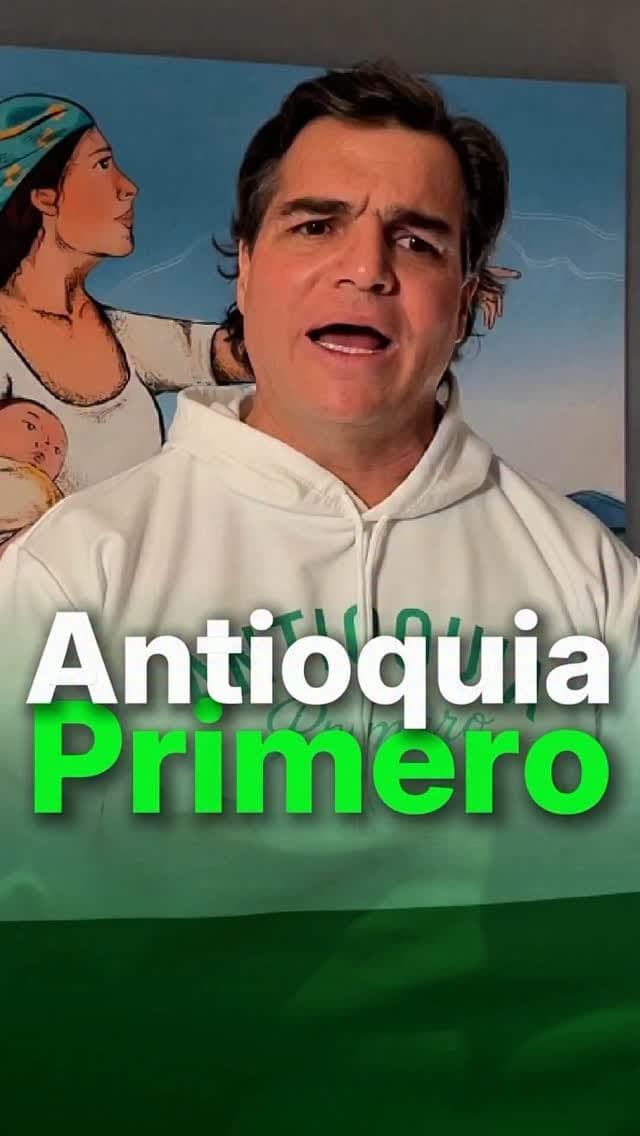 Alejandro Arbeláez A. habla a cámara con un buzo blanco, frente a un mural