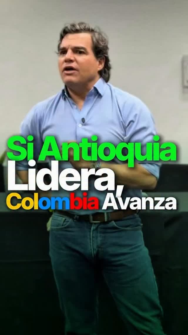 Alejandro Arbeláez A. habla ante un grupo en un salón, con camisa azul
